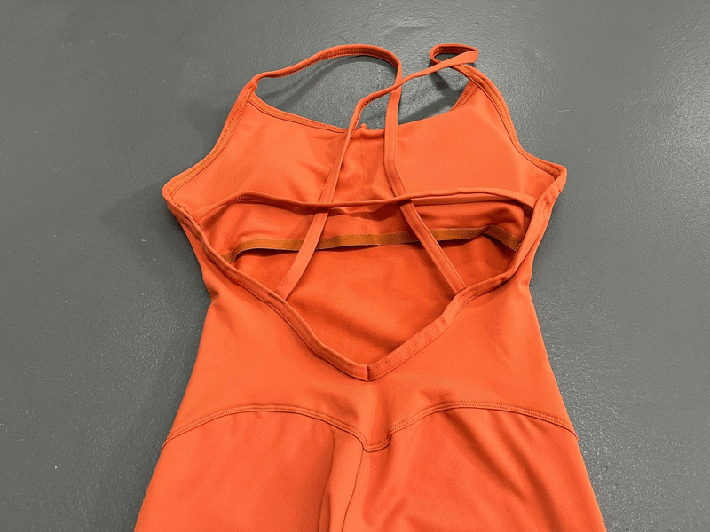 Open back view of orange female V-neck seamless yoga jumpsuit, showcasing the breathable and anti-wrinkle fabric design.